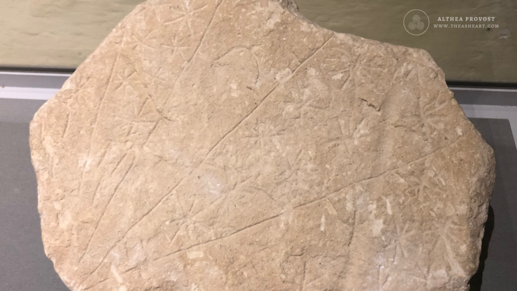 Irregular stone tablet engraved with multiple star‑like symbols and radiating line patterns.