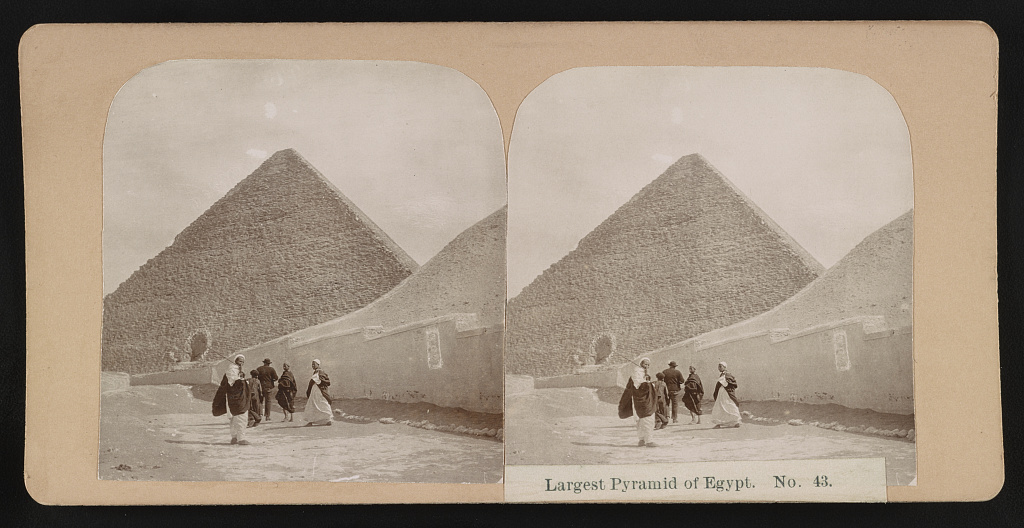 Chevron-shaped structure above the Great Pyramid entrance with figures walking near the base in a c. 1900 stereograph