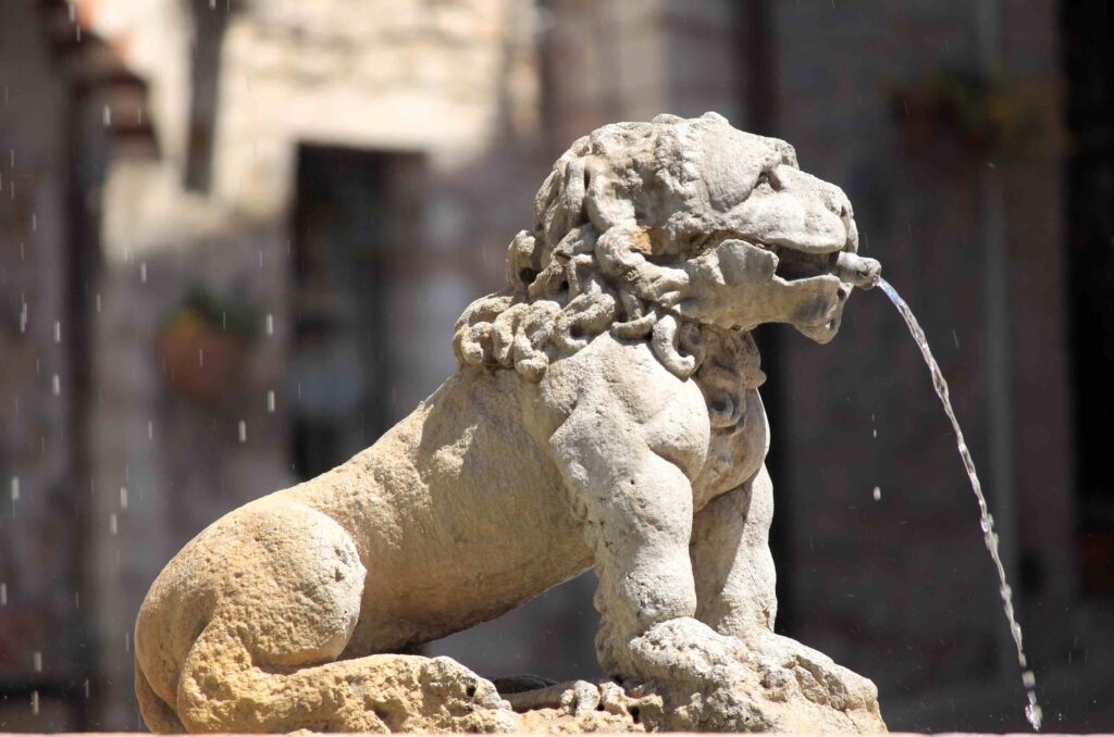 Saint Francis Walking Tour close‑up of a lion spout at the Fontana dei Tre Leoni in Assisi, Italy.