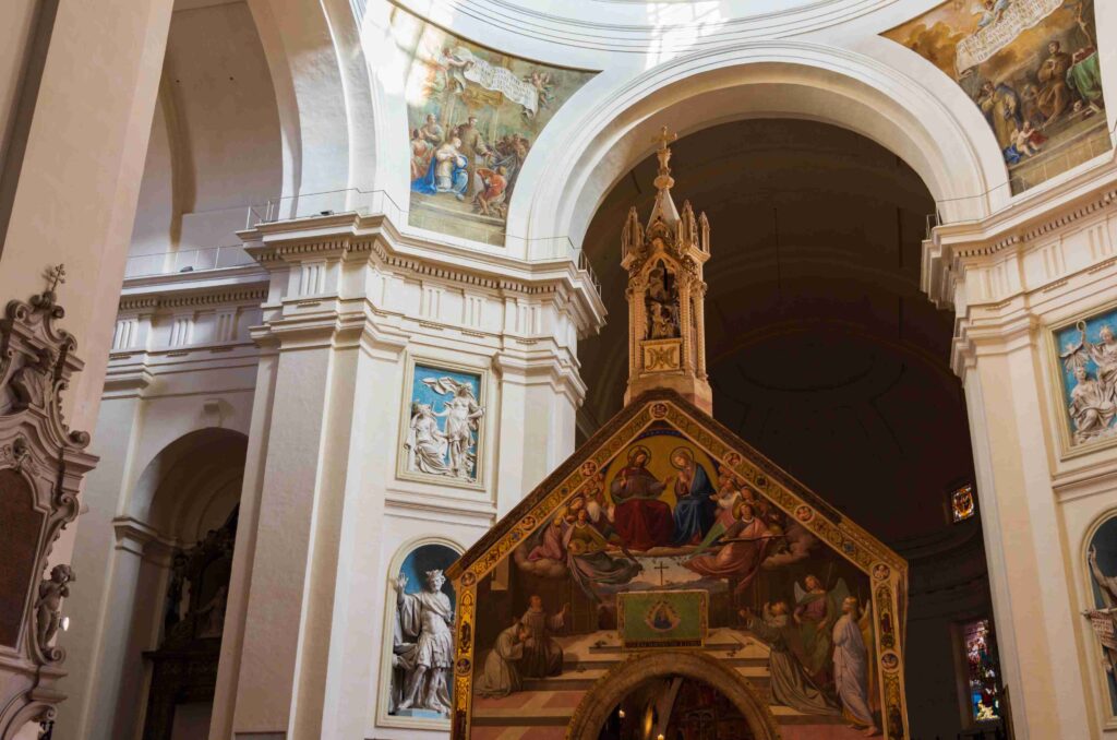 Saint Francis Walking Tour with Althea Provost. Interior of a church with white arches, frescoes on curved ceilings, and a gold ornate altar.