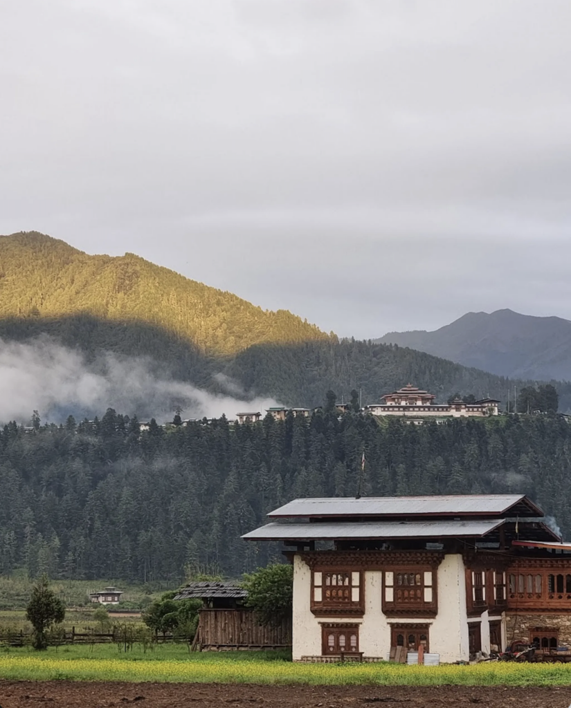 Starseed Bhutan Adventure with Althea Provost — exterior of ABC Eco Lodge with traditional Bhutanese architecture and forested mountain backdrop.