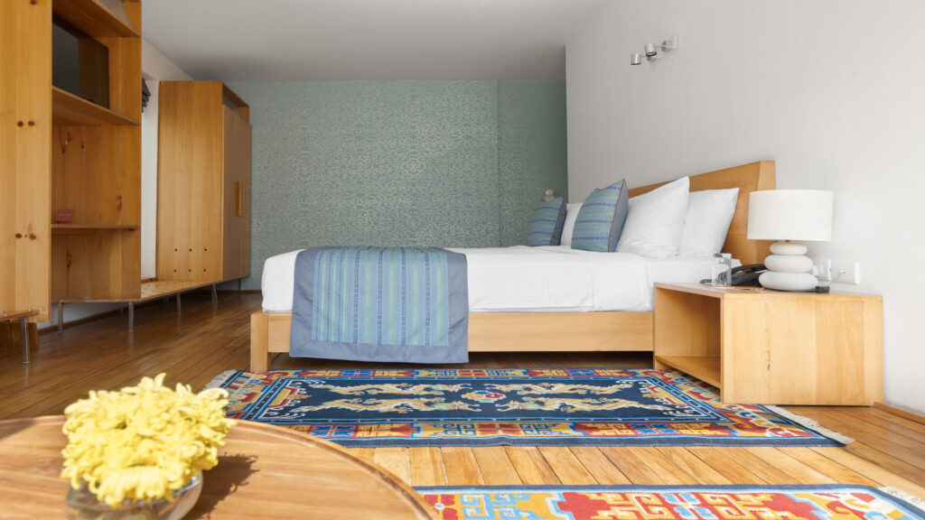 Starseed Bhutan Adventure with Althea Provost — premium suite bedroom at Zhiwaling Ascent with blue accents, warm wood tones, and modern Bhutanese decor.
