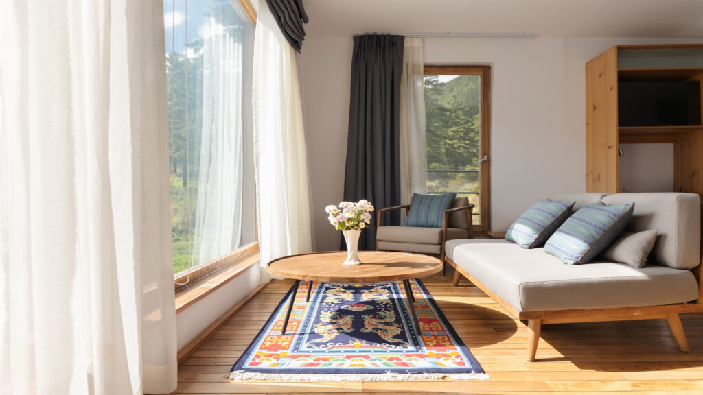 Starseed Bhutan Adventure with Althea Provost — premium suite living room at Zhiwaling Ascent with forest‑view windows and modern Bhutanese design.